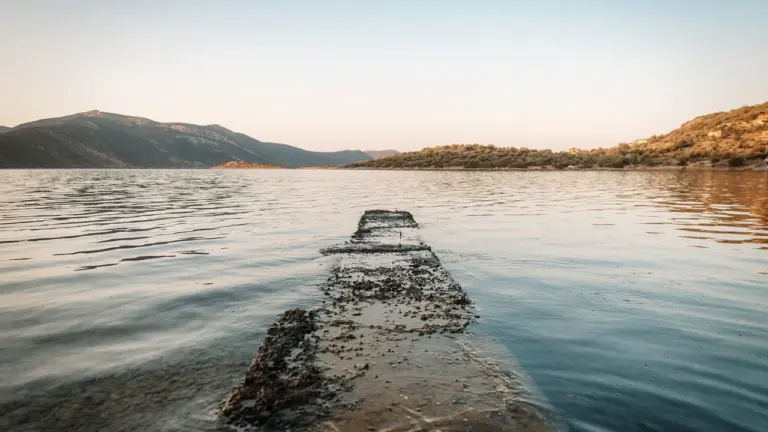 Betoninis lieptas ežere vasaros metu, primenantis apie saugų poilsį prie vandens telkinių.