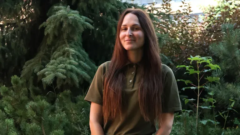 Jauna moteris ilgais tamsiais plaukais vilki chaki spalvos karinę uniformą gamtos fone.