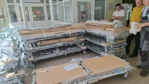 Ligoninės koridoriuje sustatytos naujos, išardytos ir į polietileną supakuotos medicininės lovos su vyrais.
