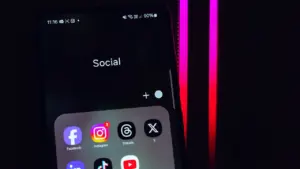Išmanusis telefonas su atidarytu socialinių tinklų programėlių aplanku ekrane
