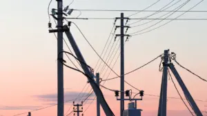 Elektros stulpai ir laidai saulėlydžio fone primenantys gedimų šalinimo darbus Zarasuose.