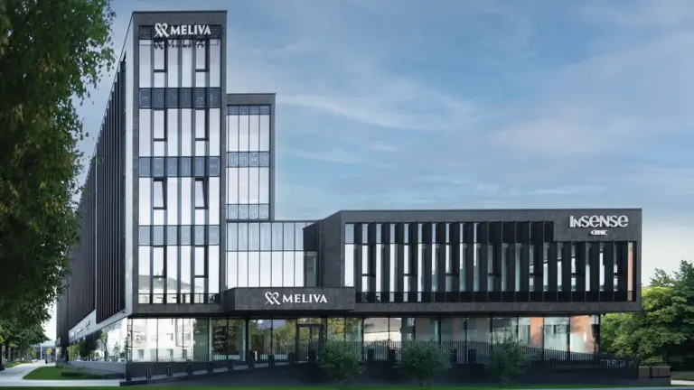 Modernaus tamsaus pastato su „Meliva“ ir „Insense“ klinikos logotipais eksterjeras saulėtą dieną.