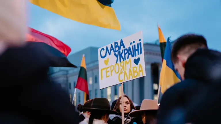 Lietuviai dalyvauja proteste laikydami Ukrainos vėliavą ir plakatą su užrašu „Slava Ukraini“.