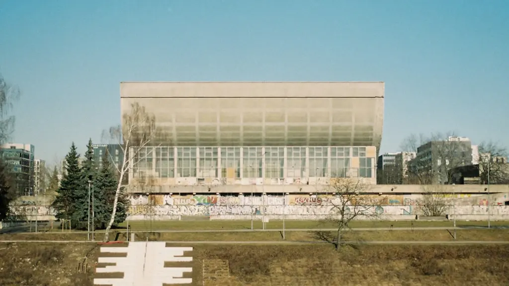 Šiuolaikinis Vilniaus sporto rūmų pastatas su stikliniu fasadu šalia upės Vilniuje