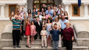 Didelė šeima pozuoja prie istorinio pastato laiptų Šeimos kortelės renginio proga Prienuose.