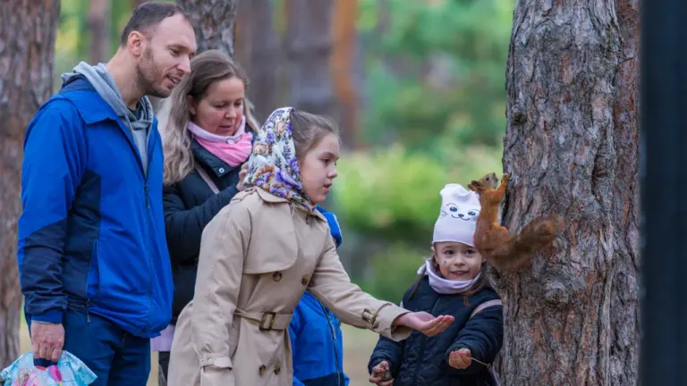 Šeima miške maitina voverę, pabrėžiant ryšį tarp žmonių ir laukinių gyvūnų