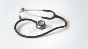 Medicininis stetoskopas ant balto pagrindo atstovaujantis profesionalią medicinos priežiūrą ir konsultacijas.