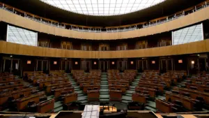 Tuščia parlamento posėdžių salė su mediniais baldais ir šviesiu stogu